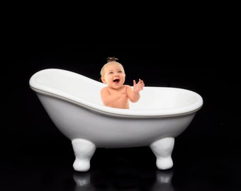 Puede incluir: Una bañera de porcelana blanca con un niño pequeño sentado dentro, sonriendo y aplaudiendo.