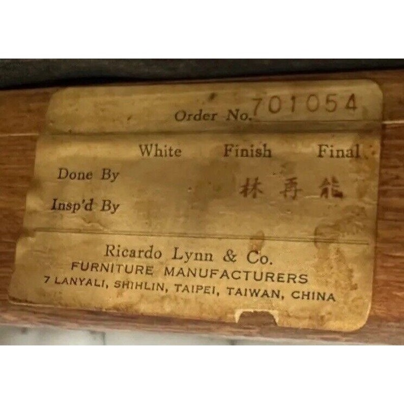 May include: A close-up of a vintage furniture label. The label is a light tan color with black text. It includes the order number 701054, the words "White Finish Final", and the name "Ricardo Lynn & Co. FURNITURE MANUFACTURERS".