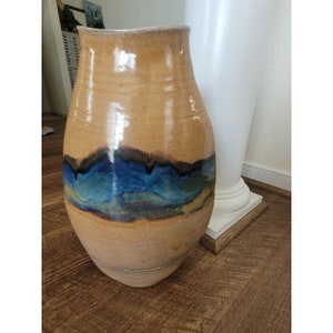 May include: A large, brown ceramic vase with a blue and gold glaze. The vase has a rounded body and a wide opening.