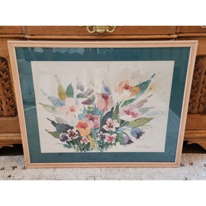 May include: A framed watercolor painting of a bouquet of pink, white, and yellow flowers with green leaves. The flowers are arranged in a vase and the background is a light blue.