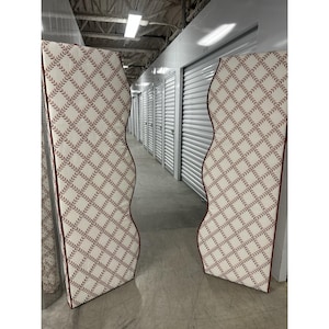 May include: Two decorative headboard panels with a cream-colored fabric featuring a repeating pattern of burgundy leaves. The panels have a wavy edge and a burgundy border. The headboards are in a storage unit.