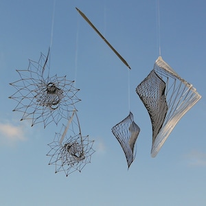 May include: A mobile sculpture featuring three geometric shapes suspended from the ceiling. The shapes are crafted from wire and hang from delicate strings. The sculpture is set against a backdrop of a blue sky.
