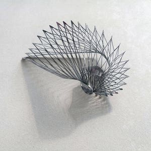 May include: A silver metal sculpture in the shape of a spiral, with a delicate, intricate design.