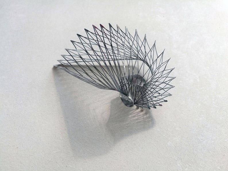 May include: A silver metal sculpture in the shape of a spiral, with a delicate, intricate design.