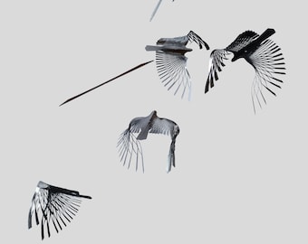 May include: Five abstract metal sculptures of birds in flight, with intricate, geometric wing designs. The sculptures are silver and black, and are arranged against a light gray background.