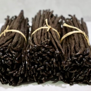 May include: Three bundles of dried vanilla beans tied with twine. The beans are dark brown and have a glossy finish.
