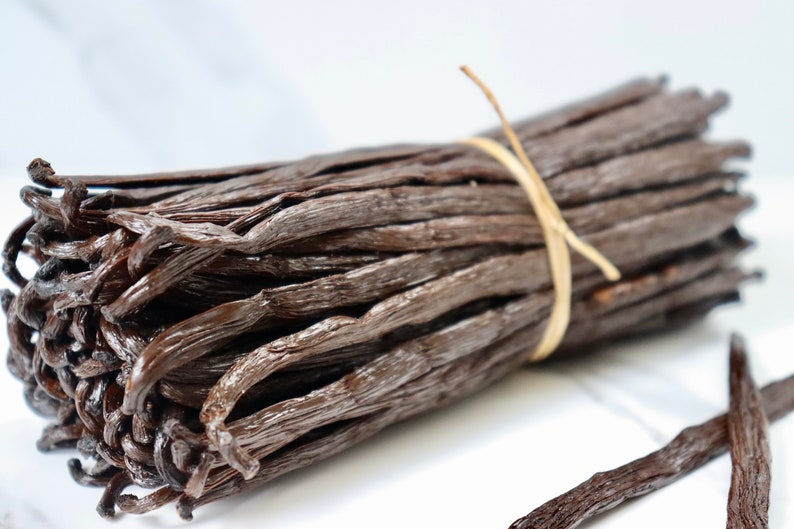 May include: A bundle of dried vanilla beans tied together with twine. The beans are dark brown and have a glossy finish.