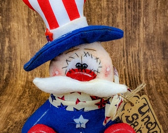 May include: A handmade patriotic doll dressed in red, white, and blue with a top hat and a tag that says "Uncle Sam".