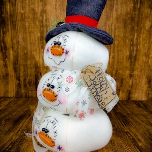 Pu&ograve; includere: Una statuetta di pupazzo di neve a tre livelli con un cappello a cilindro blu e un nastro rosso. Il pupazzo di neve &egrave; decorato con fiocchi di neve bianchi e un'etichetta che dice "Holly & Jolly Friends".
