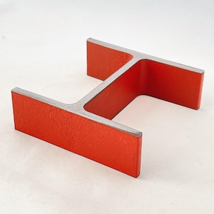 May include: A red metal H-shaped object with a textured surface. The object is made of metal and has a bright red color.