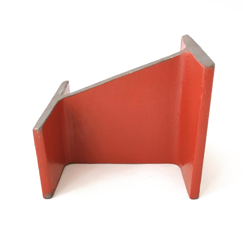 May include: A red metal bookend shaped like an upside down L. The bookend has a smooth, glossy finish.