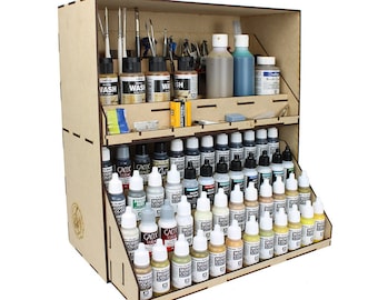 Op de afbeelding: Een houten verfopslagorganisator met meerdere planken. De organisator is gevuld met rijen kleine flesjes acrylverf in verschillende kleuren. De flesjes zijn gelabeld met de merknaam "Model Color".