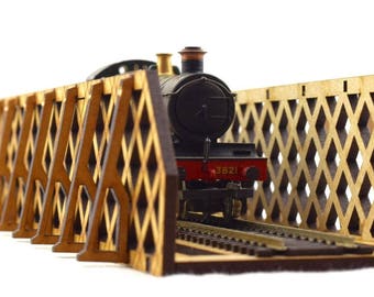 May include: A wooden model train bridge with a black and red steam engine passing through. The bridge has a diamond-shaped lattice design.