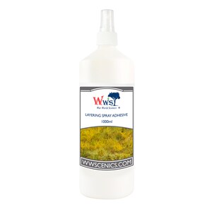 May include: A white plastic bottle with a spray nozzle, labeled "Layering Spray Adhesive" with a 1000ml capacity. The label features a logo and a depiction of yellow and green grass. The website address WWSCENICS.COM is also visible.