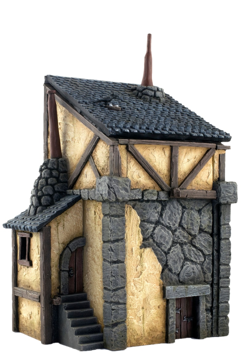 May include: A miniature stone and wood building with a gray tiled roof, two chimneys, a door, and a set of stairs. The building has a rustic, medieval aesthetic.