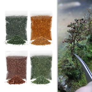 Può includere: Quattro bustine di plastica trasparente contenenti materiali per modellismo granulati in verde scuro, arancione, marrone rossastro e verde chiaro, con una pinzetta metallica che posiziona un albero in miniatura su un paesaggio verde.