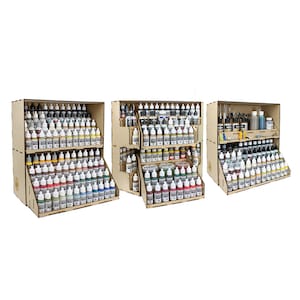 Puede incluir: Tres estantes de madera para almacenar pintura con múltiples filas de pequeños frascos de pintura. Los estantes están apilados uno encima del otro y están hechos de madera marrón claro. Los frascos de pintura están dispuestos en filas y son de varios colores.