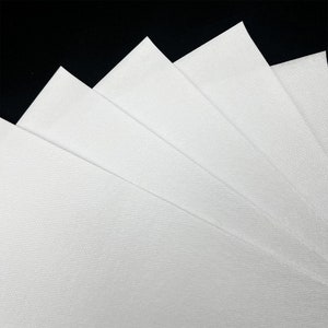 May include: A stack of five rectangular sheets of white paper arranged in a fan pattern. Each sheet features a fine, uniform textured surface with a subtle grid-like pattern visible across the material. The edges are straight and clean-cut.