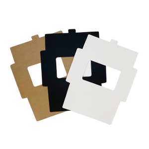 May include: Three windowed boxes, one brown, one black, and one white. The boxes are made of cardboard and have a rectangular shape with a cut-out window in the center.