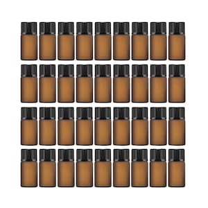 May include: A grid of thirty-six small amber glass bottles with black ribbed screw-on caps. Each bottle has a cylindrical body with a matte finish, arranged in four rows of nine, creating a uniform collection of identical containers.
