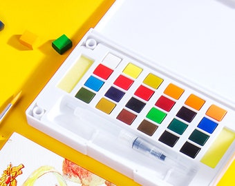 May include: A white plastic watercolor paint set featuring twenty-four rectangular pigment pans in various colors, including red, blue, yellow, green, and brown. The set includes a clear water brush pen and two yellow sponges in a hinged case.