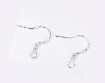 May include: A pair of silver-toned metal earring hooks featuring a curved wire design, a small coiled spring detail, and a circular loop at the bottom for attaching jewelry components. These findings are designed for creating dangling earrings.