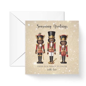 Könnte beinhalten: Quadratische Grußkarte mit weißem Umschlag, die drei Nussknacker-Figuren in roten und goldenen Uniformen zeigt. Die Karte trägt die Aufschrift "Seasoning Greetings" und "From our family to yours with love" auf goldenem Glitzerhintergrund.