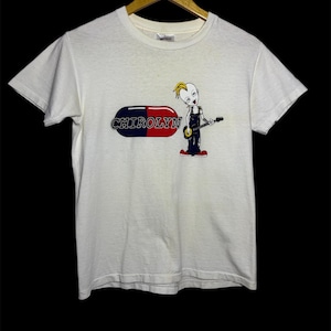 May include: White t-shirt with a cartoon character playing a guitar and the text "CHIROLYN" printed on it.