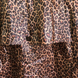 May include: A brown and black leopard print fabric with a single black button.