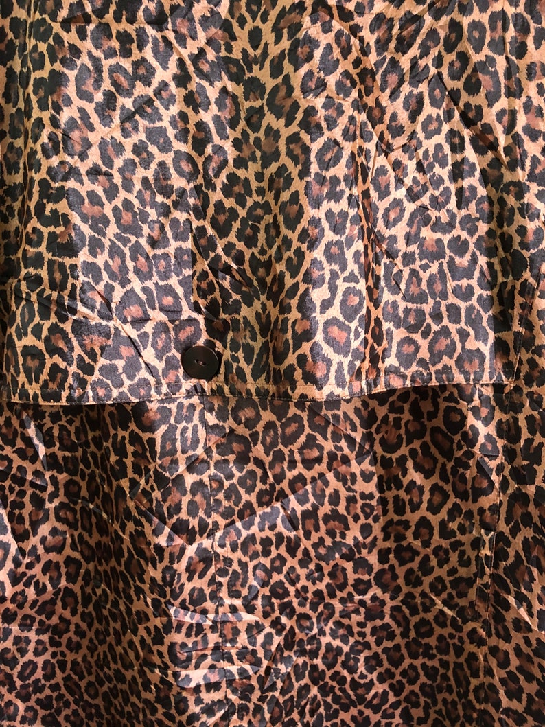 May include: A brown and black leopard print fabric with a single black button.