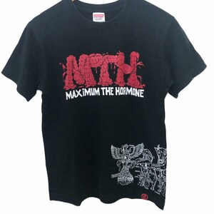 Puede incluir: Camiseta negra con un gráfico rojo de la banda "Maximum the Hormone" con su logotipo "MTH" en sangre goteando. La camiseta tiene un gráfico blanco en el lado derecho de una ilustración anatómica estilizada de un humano.