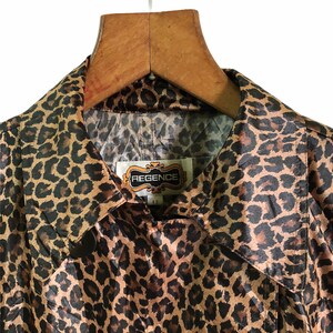 May include: A brown and black leopard print satin jacket with a collar and a label that reads "REGENCE" in gold lettering.