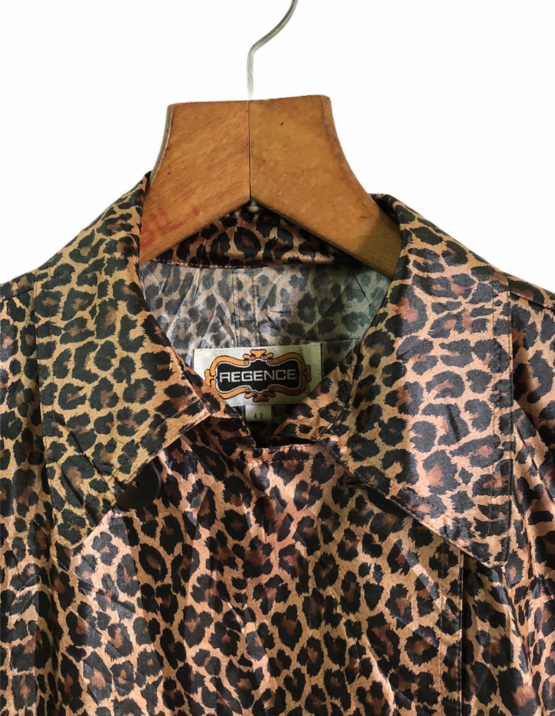 May include: A brown and black leopard print satin jacket with a collar and a label that reads "REGENCE" in gold lettering.