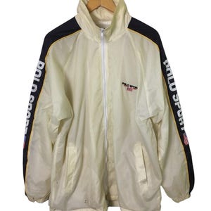 May include: A vintage white windbreaker jacket with black and yellow stripes on the sleeves. The jacket has a zipper closure and the text "POLO SPORT" is printed on the front.