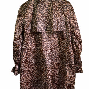 May include: A long-sleeved leopard print raincoat with a button closure and a belt at the back.
