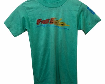 May include: A green short-sleeved t-shirt with the words "Days End" printed in colourful letters on the front.