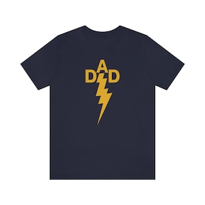 Puede incluir: Una camiseta azul marino con un gráfico de rayo amarillo y el texto "A DAD" dentro del rayo.