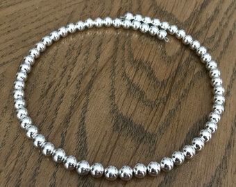 May include: A silver necklace made of round beads.