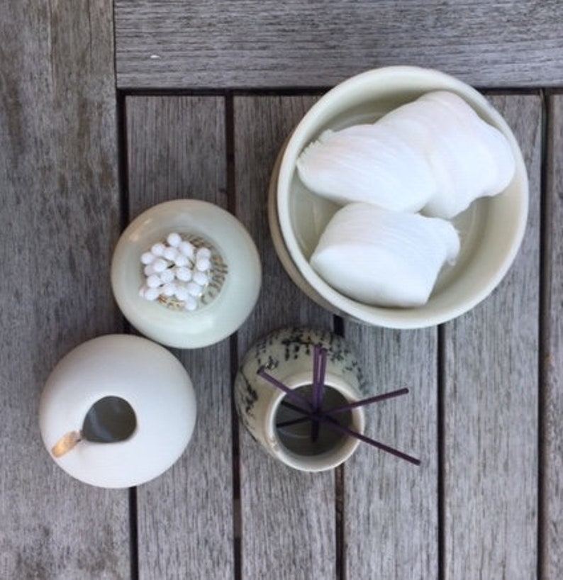 May include: Three ceramic bowls on a wooden surface. One bowl contains white cotton balls, another contains white cotton candy, and the third bowl contains incense sticks.
