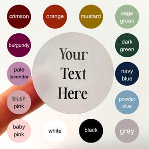 May include: A round sticker with the text "Your Text Here" in black. Surrounding the sticker are color swatches labeled crimson, orange, mustard, sage green, burgundy, pale lavender, blush pink, baby pink, white, black, and grey.