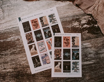 May include: Two sheets of A5 book cover stickers featuring popular book covers. The stickers are printed on white paper and feature a variety of book covers, including "The Atlas Six", "A Court of Thorns and Roses", "Piranesi", and "Dune".