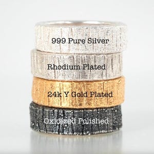 May include: Four silver rings stacked on top of each other. The top ring is labeled "999 Pure Silver", the second ring is labeled "Rhodium Plated", the third ring is labeled "24k Y Gold Plated", and the bottom ring is labeled "Oxidized Polished".