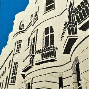 May include: Black and white linocut print of a building with a curved facade and multiple windows. The building has a fence in front of it.