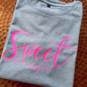 Może przedstawiać: Szara koszulka z napisem "Sweet but psycho" w r&oacute;żowych literach.