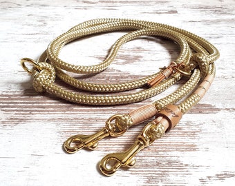 May include: A beige rope dog leash with two gold metal clips and a brown leather accent.