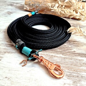 Op de afbeelding: Zwarte touwhalster voor honden met een turquoise en koperen accent en een koperen haak.