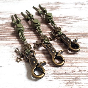 May include: Three green and brown keychains with metal clasps. Each keychain has a star charm and green beads.