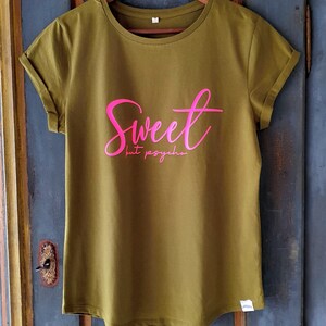 Może przedstawiać: Zielona koszulka z napisem "Sweet but psycho" w r&oacute;żowych literach.