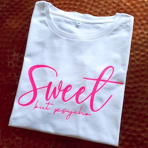 Może przedstawiać: Biała koszulka z r&oacute;żowym napisem "Sweet but psycho".