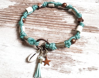 May include: A turquoise and brown knotted necklace with a seashell, star, and tassel charm. The necklace features white cylindrical beads and copper-colored accents. The design includes a metal ring clasp.
